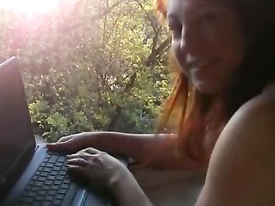 Сидя за ноутбуком голая девушка ласкает натуральную грудь на камеру
